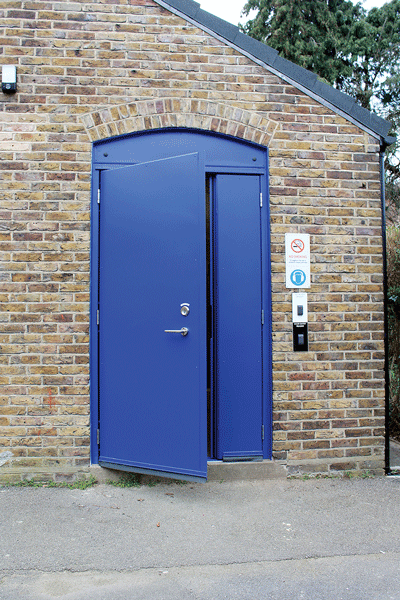 Technocover LPCB certified twinleaf door, with a primary door leaf, entry and exit ironmongery, and an arched head blanking plate.
